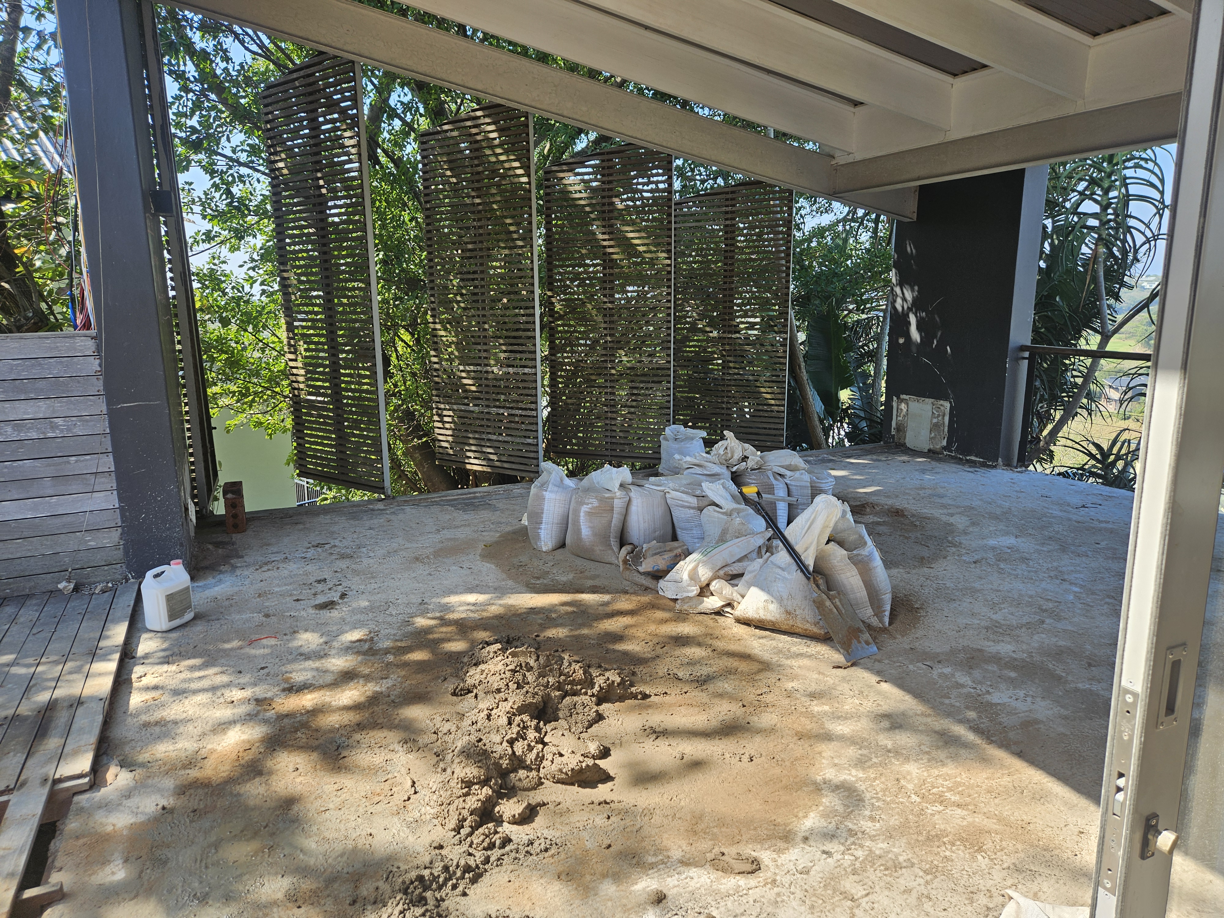 Covered patio flooring preparation with building materials and timber privacy screens on coastal estate