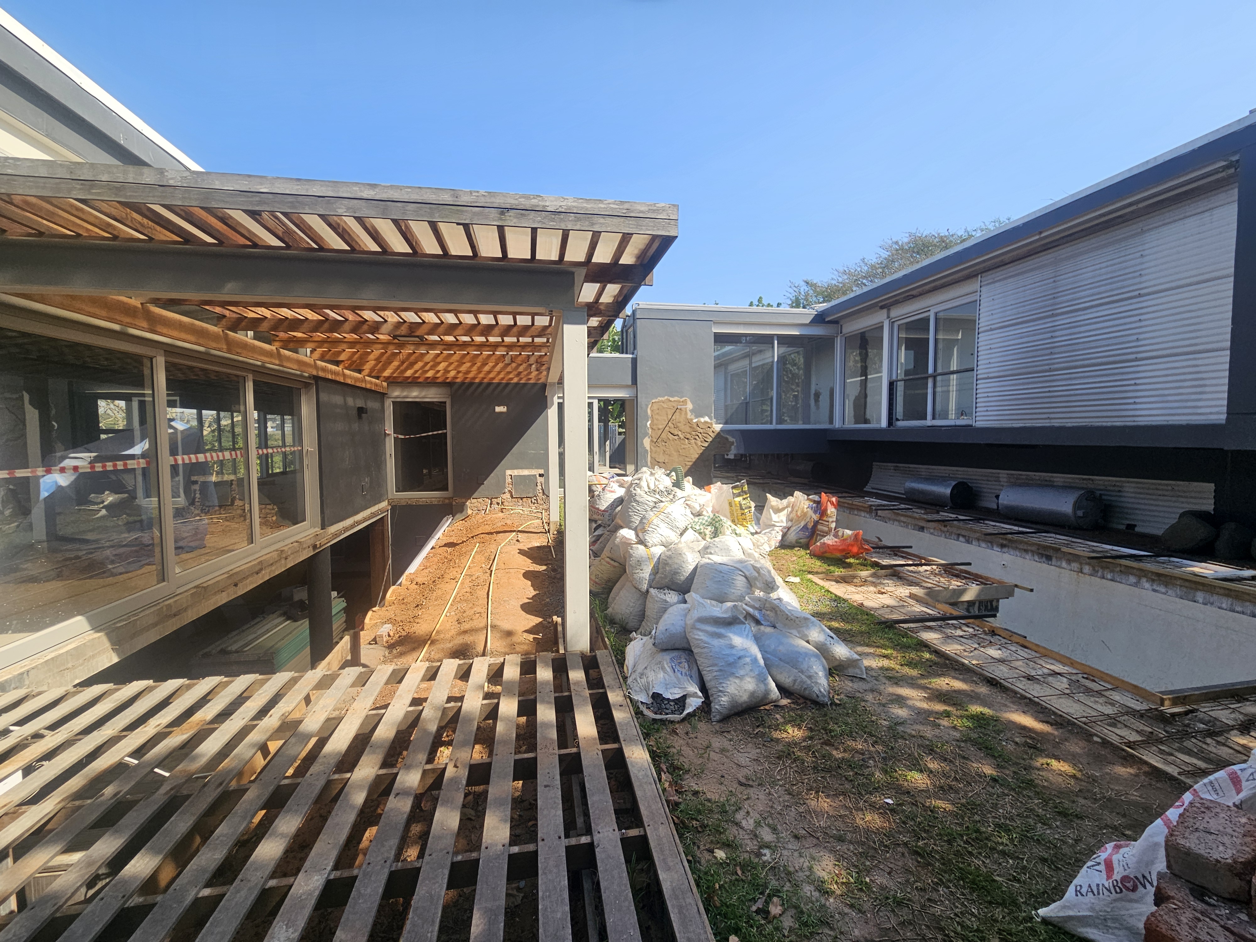 Wide exterior view of home renovation showing timber pergola new decking and landscaping groundwork