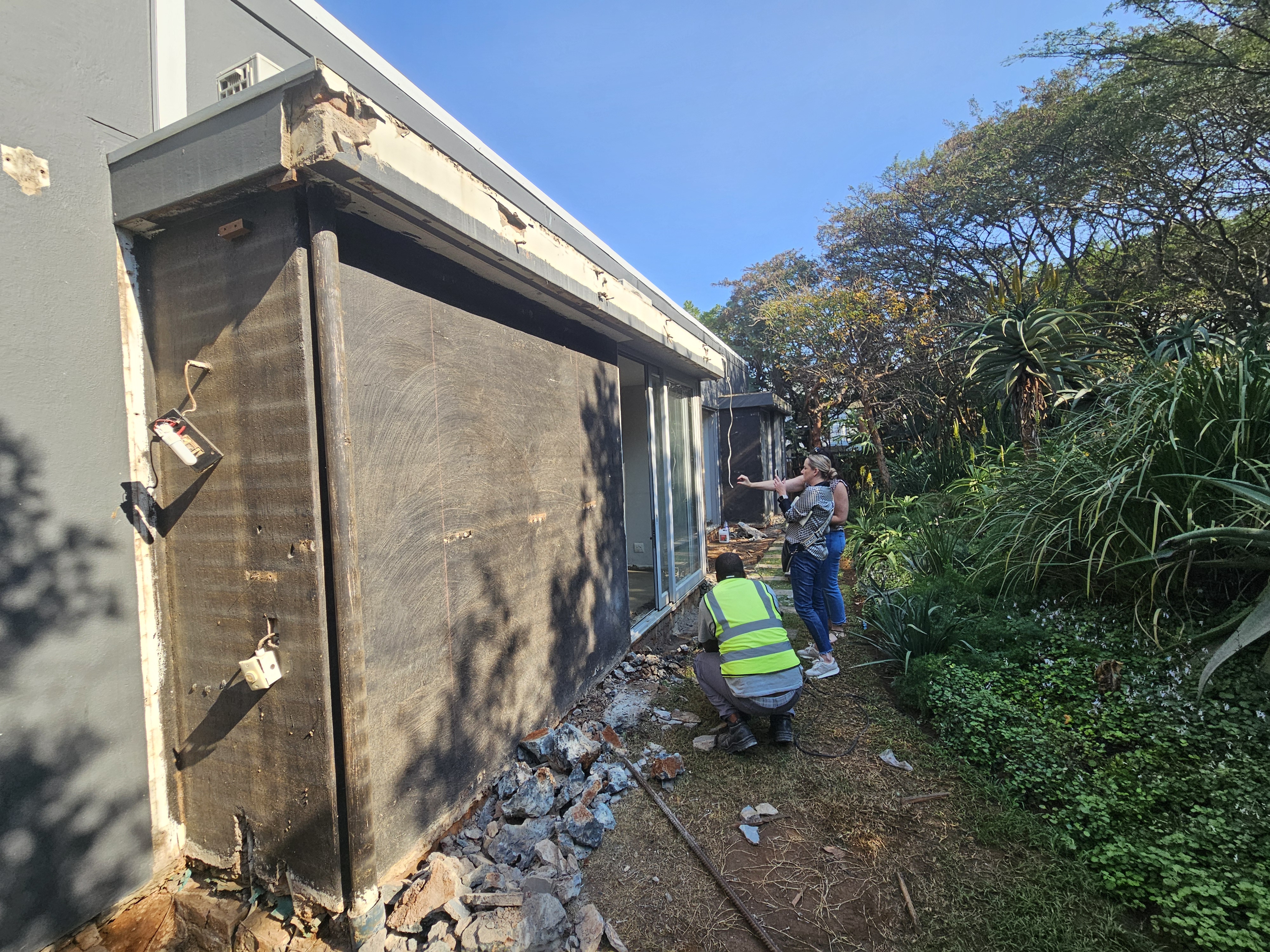Interior designer on site inspecting exterior wall reconstruction with contractor during home renovation